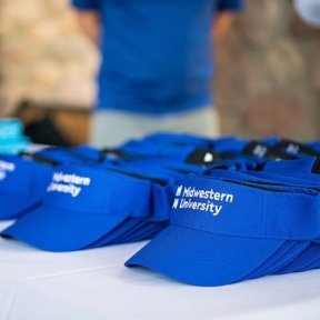 Blue sun visors with the words Midwestern University sitting on a table.