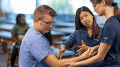students checking arm of PT patient