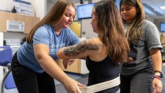 OT students practice using belts to help patients stand.