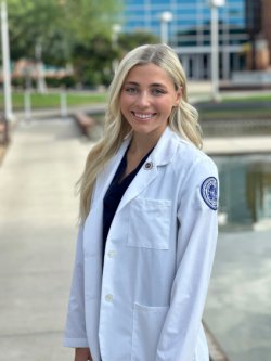 Podiatry student Audrey Diaz stands in her white coat on Glendale campus