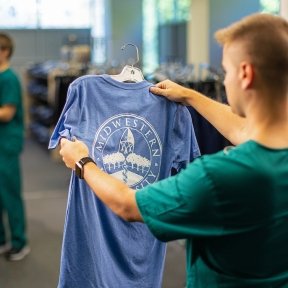Student looking at t-shirt while student pays at cash register