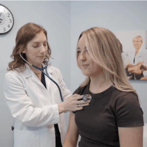 Rachel Locker, MWU Physician Assistant Student, listens to a patient's heart through a stethoscope.