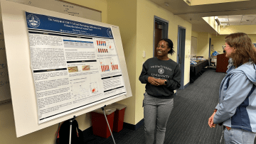Veterinary Medicine student presents her poster presentation to another student.