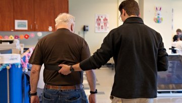 Student assists elderly man walking