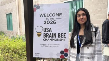 High school student Shireen Arora stands next to the USA Brain Bee sign at the competition