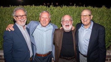 Four alumni laughing and posing together outdoors at the MWU College of Osteopathic Medicine alumni reunion.