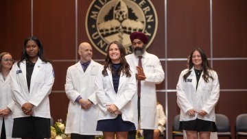 Students in the College of Health Sciences - Illinois receive their white coats on stage