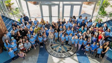 Midwestern employees stand with their children in matching blue shirts for MWU Kids Day