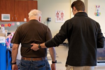 Student assists elderly man walking