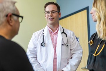 Two providers talk to patient in an exam room