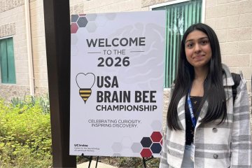 High school student Shireen Arora stands next to the USA Brain Bee sign at the competition