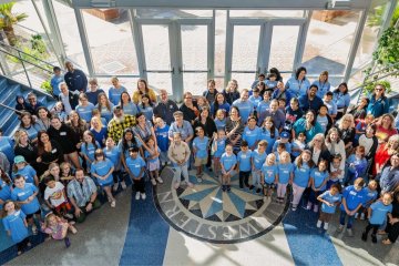 Midwestern employees stand with their children in matching blue shirts for MWU Kids Day