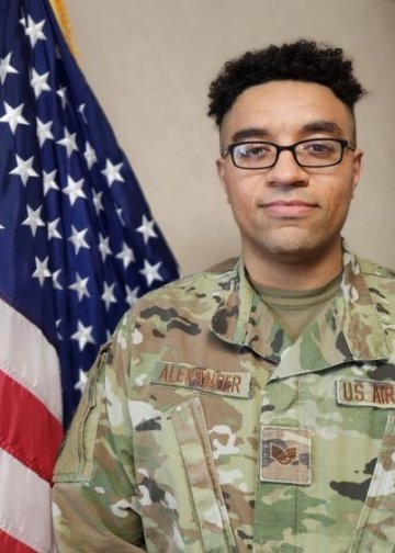 Andre Alexander poses in military uniform with flag