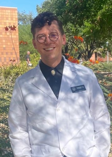 Mason Stewart-McLellan smiles at the camera outside in his white coat 