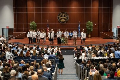 Students on stage receiving their white coats.