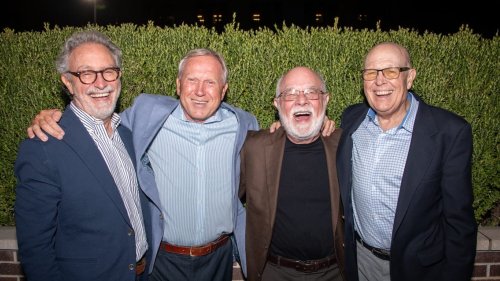 Four alumni laughing and posing together outdoors at the MWU College of Osteopathic Medicine alumni reunion.