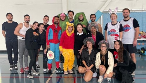 Pickleball tournament players gather for a photo, some with Halloween costumes.