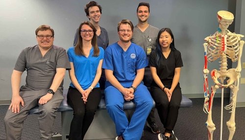 Six AZCOM Scholars sitting on bench near skeleton.