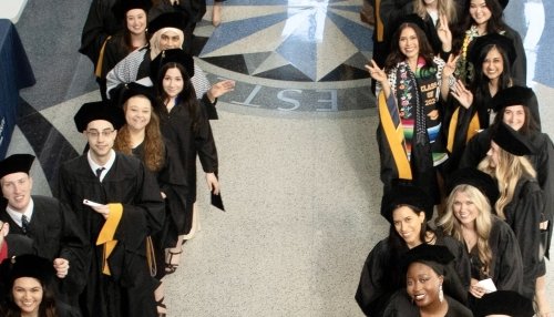 Graduates in caps and gowns lined up indoors.