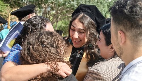 Family and friends hug and congratulate a recent graduate.