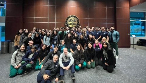 Group of students pose by University seal