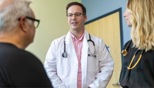 Two providers talk to patient in an exam room