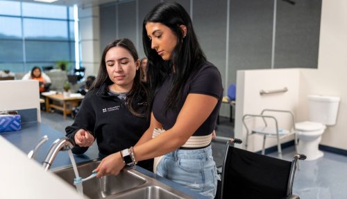 OT student assists patient with standing and brushing teeth.
