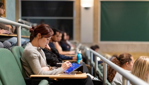 Student in lecture hall looking at IPad