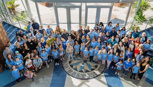 Midwestern employees stand with their children in matching blue shirts for MWU Kids Day