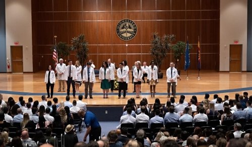 students on stage for white coat ceremony