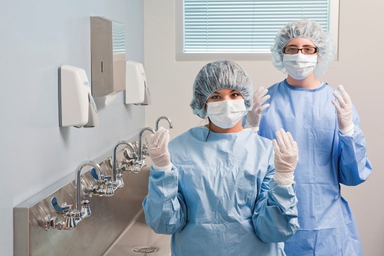Two students in scrubs in front of a cleaning area