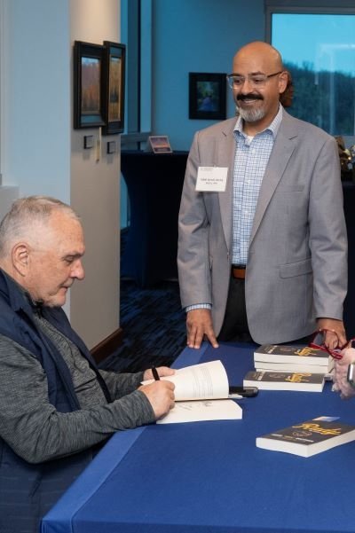 Rudy Ruettiger autographs his book for an attendee.