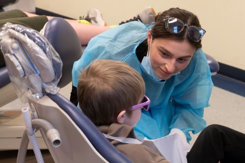 Dental student talks with boy in dental chair