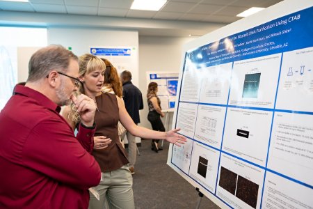 A student explains her research poster to a faculty member at KAS Research Day