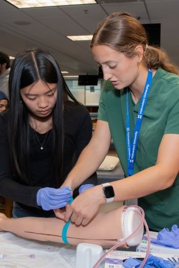HCI mentor and particpant find vein on simulated arm