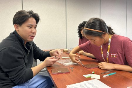 A Midwestern student teaches a high school student how to sutur