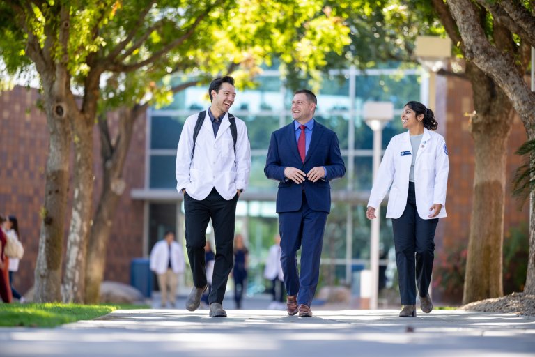 Dr. Baker walks with two students at the Midwestern University Glendale, AZ campus.